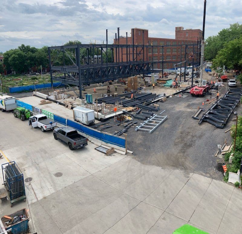 Vue d’ensemble du chantier de construction avec structure d’acier érigée, équipements lourds et montage en cours en milieu urbain réalisé par CSL Ltée