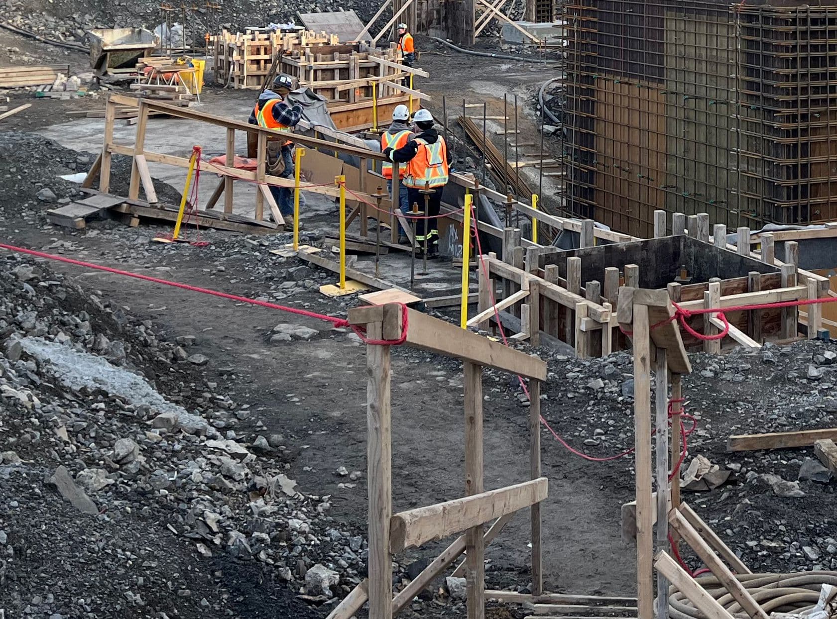 Travaux de coffrage et de bétonnage réalisés par une équipe sur un chantier industriel, avec passerelles temporaires et mesures de sécurité en place.