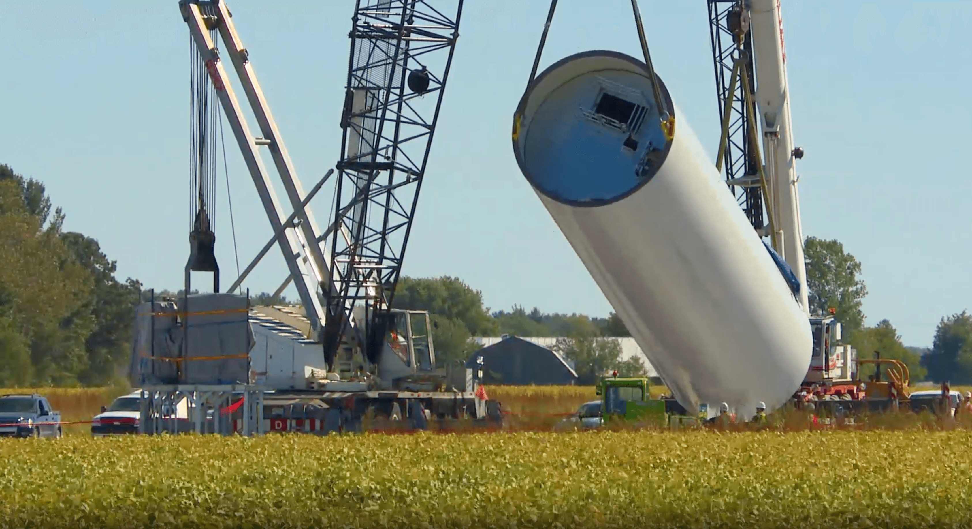 Levage et positionnement d’un mât d’éolienne à l’aide d’une grue sur un chantier de parc éolien en zone rurale.
